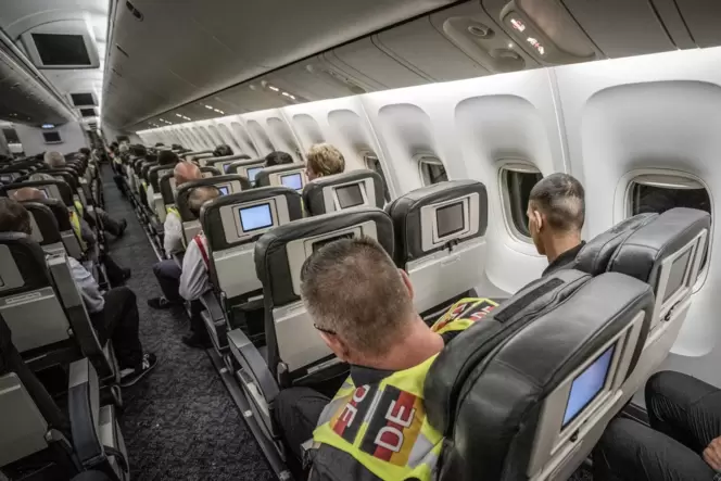Ein Polizeibeamter sitzt als »Begleiter« neben einem Afghanen, der abgeschoben wird, auf dem Flug von Leipzig nach Kabul in eine Ein Polizeibeamter sitzt als »Begleiter« neben einem Afghanen, der abgeschoben wird, auf dem Flug von Leipzig nach Kabul in eine