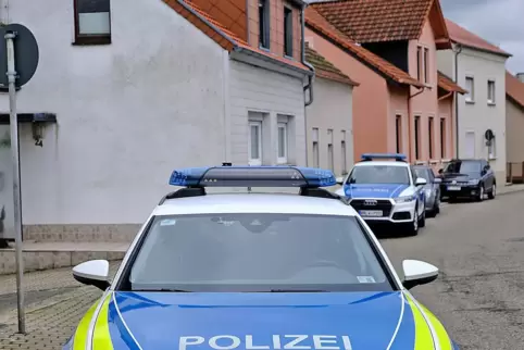 Polizeiautos halten in der Friedrich-Ebert-Straße vor Nachbarhäusern des Leichenfundorts, das Haus rechts im Bild.