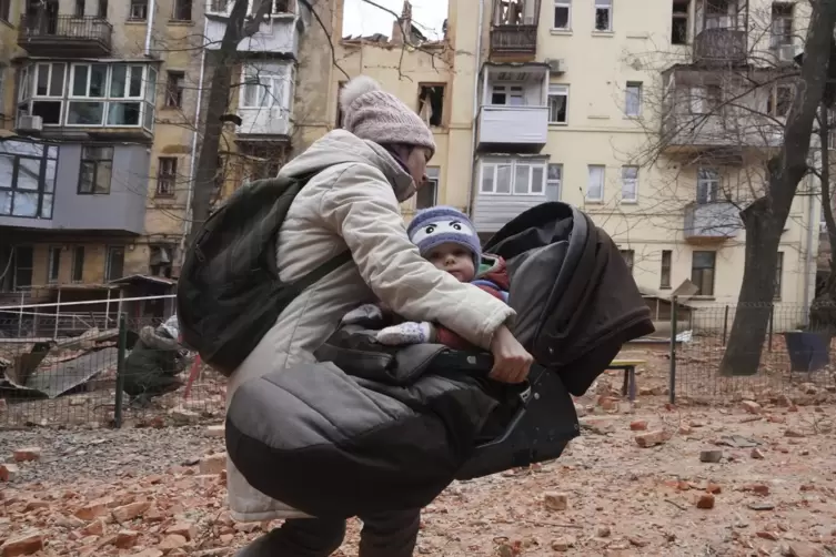 Diese Frau, die sich mit ihrem Kind aus ihrem durch russischen Beschuss zerstörten Haus im ukrainischen Charkiw rettet, ist eine