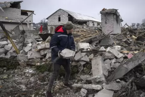 In Kiew räumt ein Anwohner Trümmer nach einem russischen Raketenangriff weg.