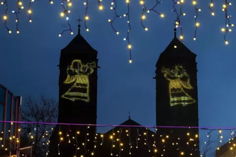 Weihnachtsbeleuchtung in Pirmasens, hier die Pirminiuskirche, durch die Lichterketten der Schlittschuhbahn gesehen. 