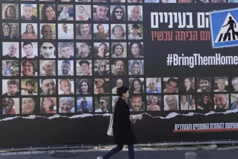  Eine Frau geht in Jerusalem an einem Plakat vorbei, das die Rückkehr der etwa 240 Geiseln fordert, die während des Hamas-Angrif
