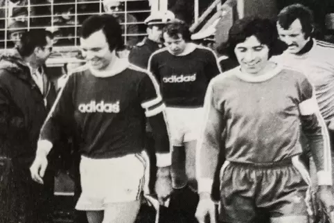 Januar 1976: Die miteinander scherzenden Kapitäne Robert Jung (rechts) und Franz Beckenbauer führen die Mannschaften des FK Pirm