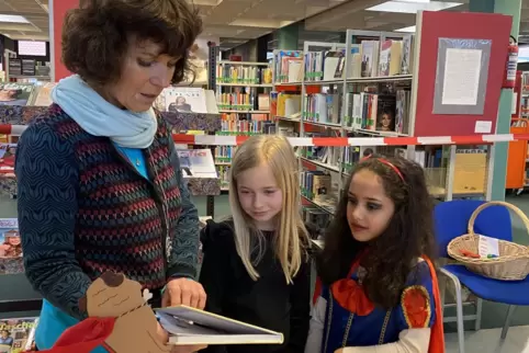 Birgit Bauer zeigt Carla (links) und Dalia die Bücher für die Aktion „Tierische Bücherhelden wecken Leselust“. Viele Titel kenne