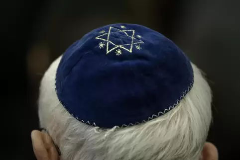 Ein Mann trägt in einer Synagoge eine Kippa mit Davidstern. 