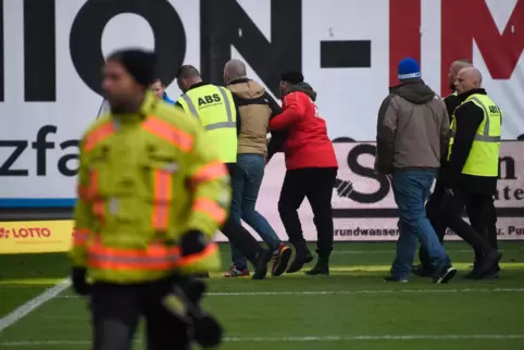 Ein Rostocker Fan, der nach dem Tor des FCK zum 3:0 auf den Platz gestürmt war, wird abgeführt. 