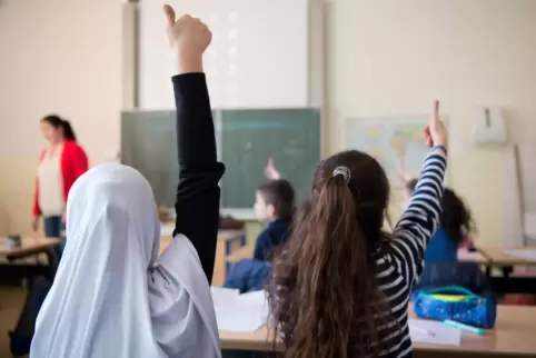 Mädchen mit ausländischen Wurzeln melden sich im Unterricht eines Gymnasiums. 