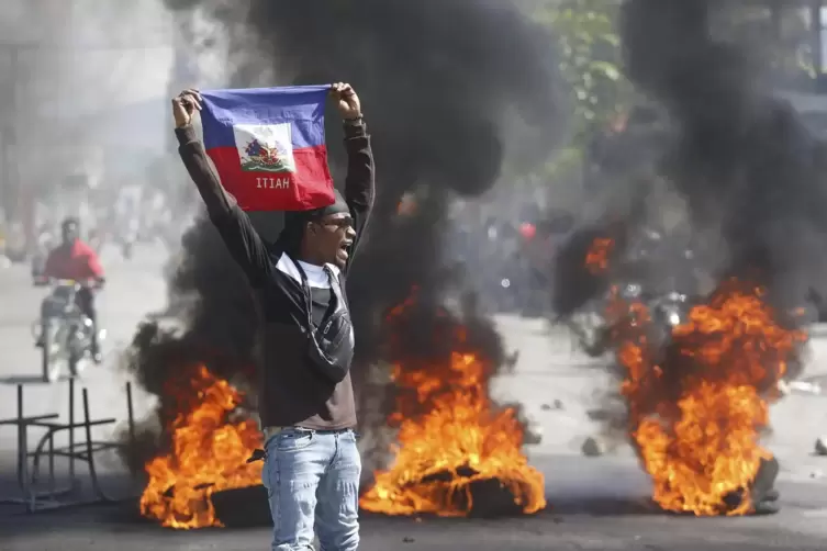 Ein Demonstrant hält eine haitianische Flagge während Protesten für den Rücktritt von Premierminister Henry hoch.