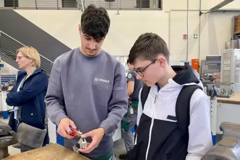 Mit Gefühl: Vögele-Azubi Anil Kirtay biegt mit einem jungen Besucher einen praktischen Smartphone-Halter zurecht.