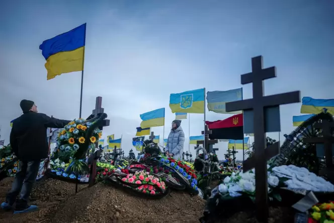 Auf dem Friedhof der Hafenstadt Odessa stellen Hinterbliebene am Grab eines gefallenen Soldaten die ukrainische Nationalflagge a