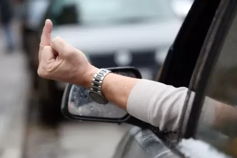 Eine Person zeigt einen Mittelfinger aus dem Autofenster