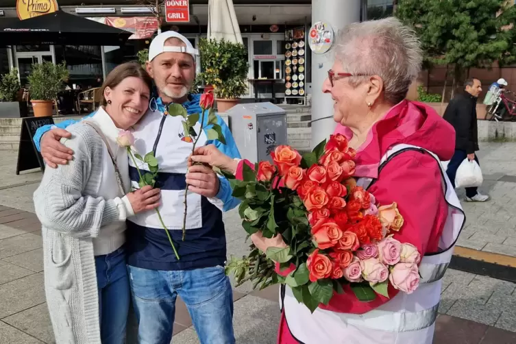 Birgitta Scheib verteilt Rosen an ein Paar auf dem Berliner Platz. 