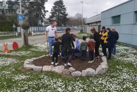 Ortsbeiratsmitglied Peter Poreba (links) sät zusammen mit den Kindern und ihren Erzieherinnen den Blumensamen ein.