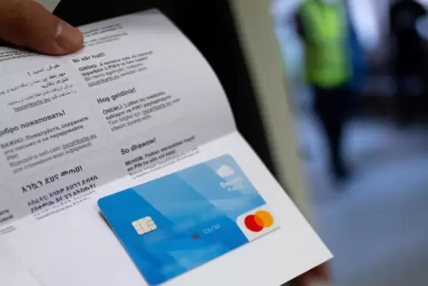 Ein Asylbewerber zeigt im Ankerzentrum eine der ersten bayerischen Bezahlkarten die er zuvor erhalten hat. 