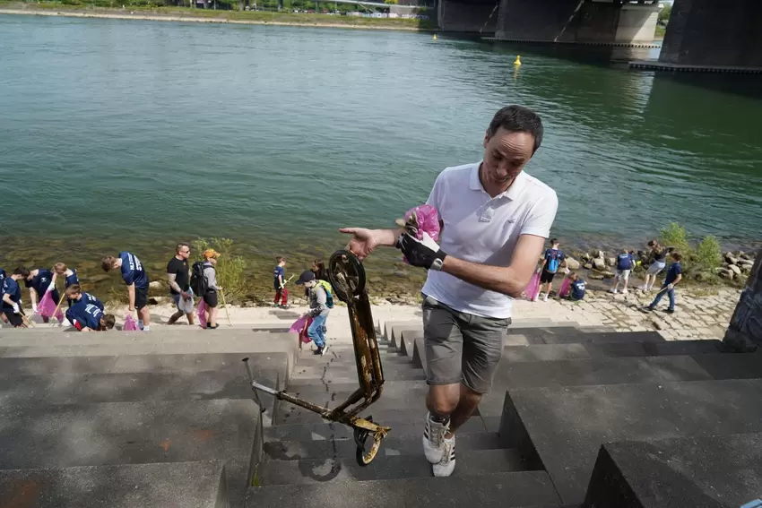 Ein schon halb verrosteter Tretroller wird von den Erwachsenen aus dem Wasser gezogen.