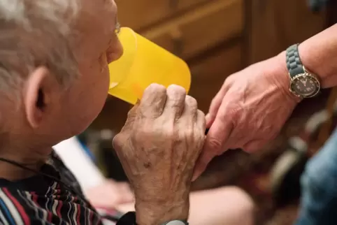 Unterstützung im Alltag: Eine ambulante Pflegerin hilft einem alten Mann beim Trinken. 