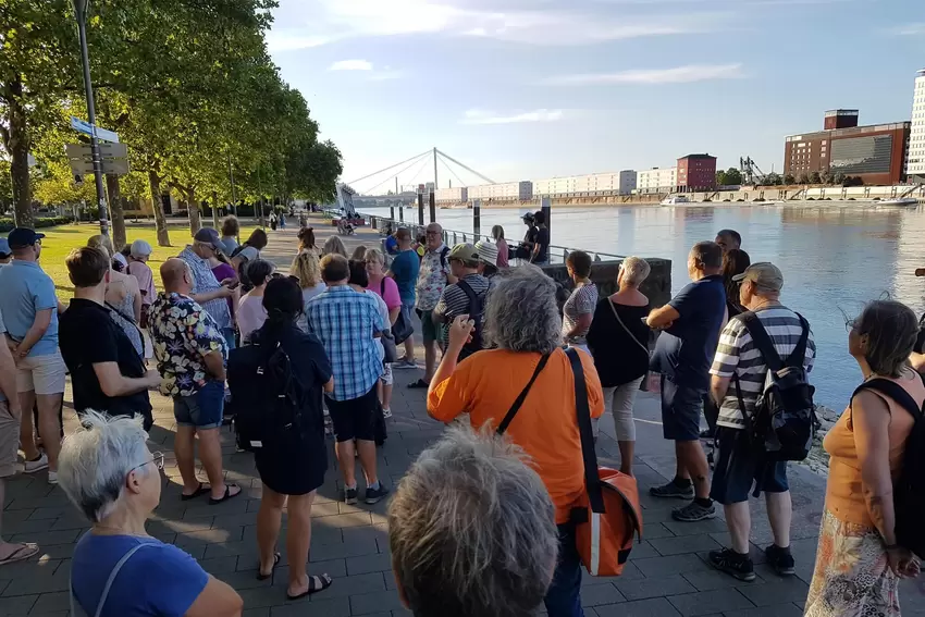 Tourteilnehmer mit ihrem Stadtführer am Rheinufer.
