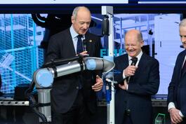 Bundeskanzler Olaf Scholz (rechts) und Siemens-Geschäftsführer Roland Busch verhandeln mit einem Roboterarm.