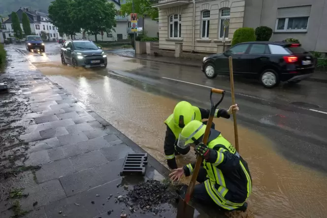 Nach unwetterartigen Regenfällen in Bad Neuenahr reinigen Feuerwehrleute Kanaldeckel. Starke Regenfälle führten in vielerorts zu