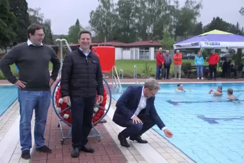 Ortsbürgermeister Steffen Blaga prüft die Temperatur des Wassers, in dem drei Unerschrockene baden. Mit dabei: Verbandsbürgermei
