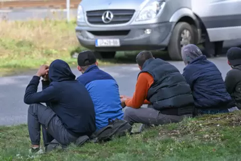 Unerlaubt eingereiste Migranten sitzen nach einem Aufgriff durch Beamte der Bundespolizei am Straßenrand nahe der deutsch-polnis
