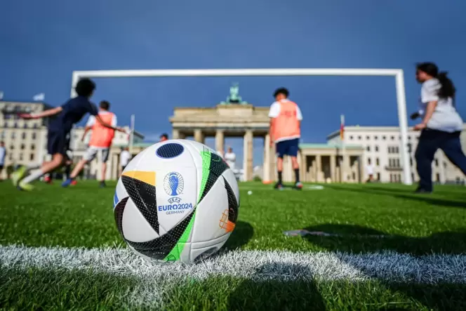 Kinder spielen in Berlin auf dem Kunstrasen vor dem Brandenburger Tor mit dem riesigen Fußballtor hinter dem offiziellen Ball fü