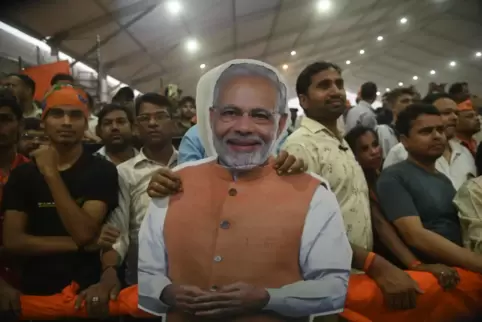 Anhänger der hindu-nationalistischen Partei BJP halten ein Plakat mit dem Gesicht des indischen Premierministers und BJP-Spitzen