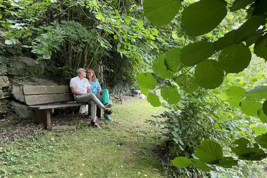 Heike und Günther Bergs sitzen abends gerne auf der hölzernen Bank jenseits des Horschbachs und blicken in den beleuchteten Gart