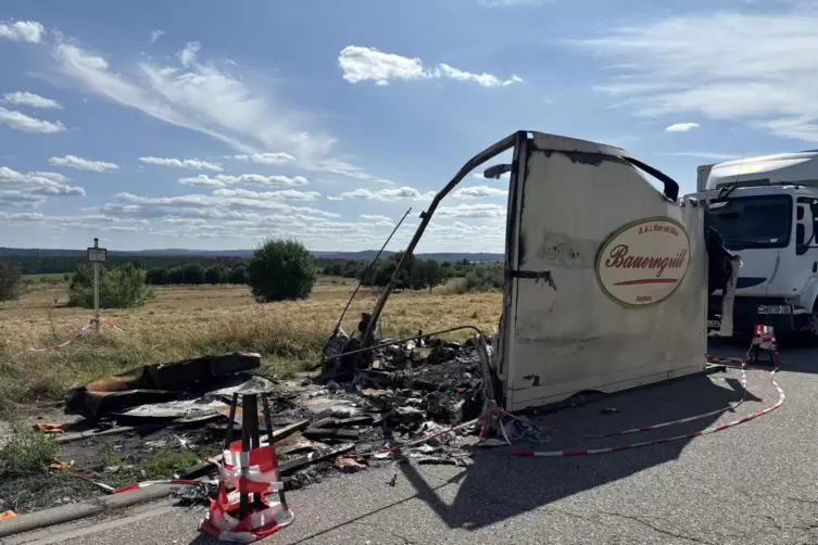 Ein abgebrannter Imbisswagen steht am Stra&szlig;enrand.