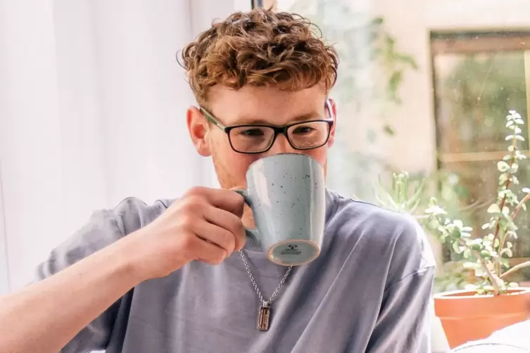 Ein junger Mann trinkt einen Kaffee.
