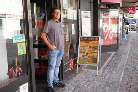 Arno Wagner mit seinem Klappschild vor der Apotheke. Im Hintergrund ist rechts ein Schaufenster des benachbarten Geschäfts zu se Arno Wagner mit seinem Klappschild vor der Apotheke. Im Hintergrund ist rechts ein Schaufenster des benachbarten Geschäfts zu se