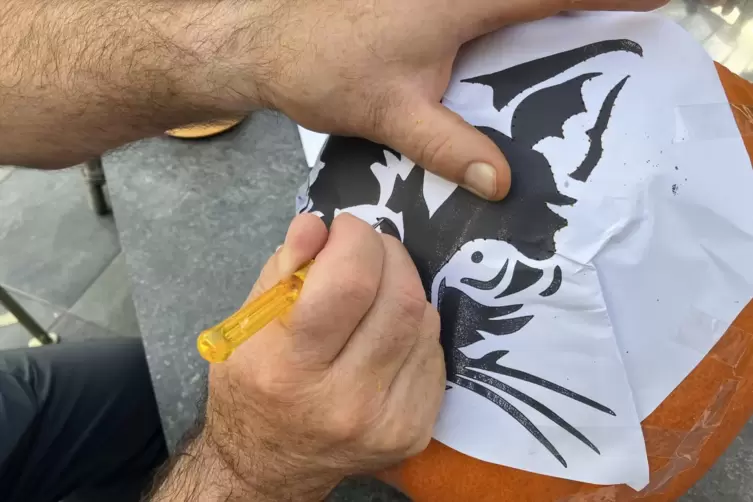 Nachdem die Schablone mit Tesafilm auf den K&uuml;rbis geklebt wurde, sticht man mit einem spitzen Gegenstand, zum Beispiel einem kle