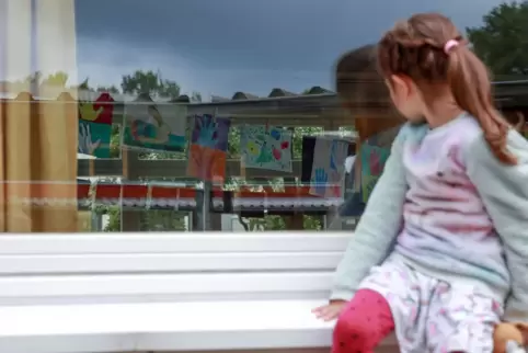 Ein Kind sitzt auf einer Fensterbank.