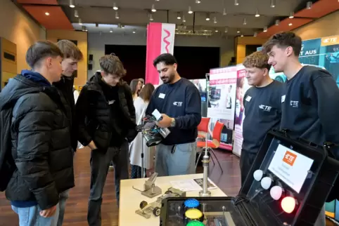 Mechatroniker Safa (Mitte, mit Gerät), Werkzeugmechaniker Elias (Zweiter von links) und Mechatroniker Jonas (links) zeigen ihr B
