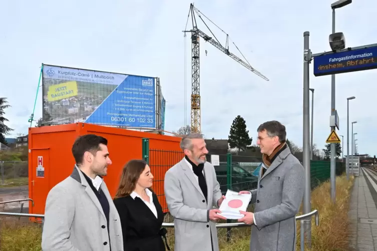 Bernhard Adams übergibt die Baugenehmigung an Projektleiter Torsten Weil. Links daneben Vertriebsleiter Maurice Roth und Hochbau