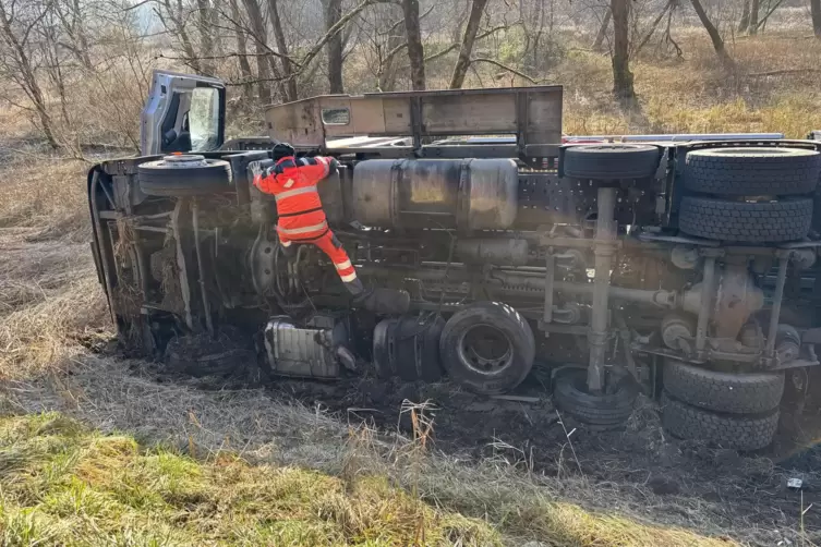 Ein Mitarbeiter des Abschleppdienstes pr&uuml;ft, wie man den Lkw samt Anh&auml;nger am besten wieder aus dem Graben ziehen kann.