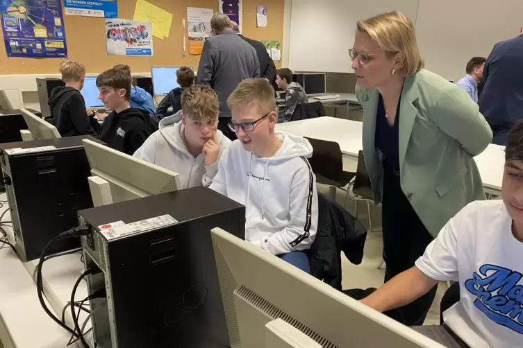 Stefanie Hubig schaut Sch&uuml;lern beim Basteln an den KI-Anwendungen &uuml;ber die Schulter.