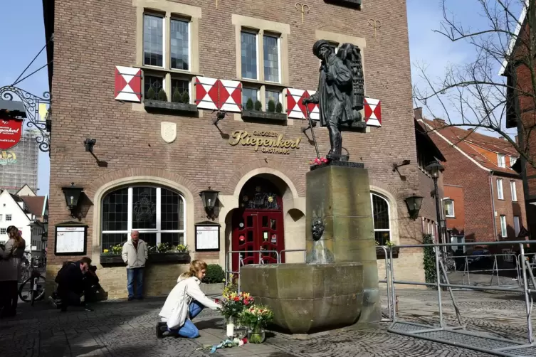 Eine Frau legt vor dem Ort des Geschehens in M&uuml;nster Blumen nieder.