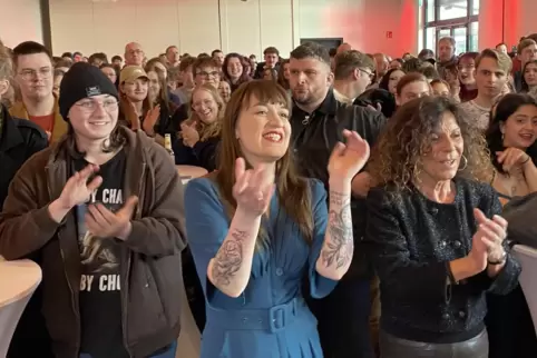Heidi Reichinnek (Mitte) präsentiert sich vor jungen Anhängern in Saarbrücken. Rechts neben ihr steht die saarländische Linken-L