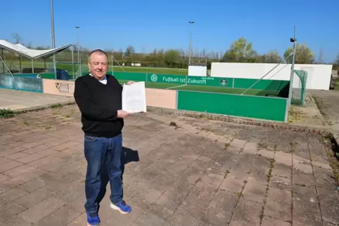 Norbert Bölger, Vorsitzender des SV Obersülzen, zeigt den Zuwendungsbescheid am Standort der geplanten McArena.