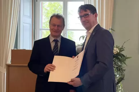 Hans-Peter Ehrhart (links) erhält seine Ruhestandsurkunde von Staatssekretär Michael Hauer. 