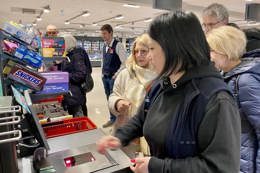 Rewe-Mitarbeiter helfen den Teilnehmern bei ihrer Premiere an der SB-Kasse.
