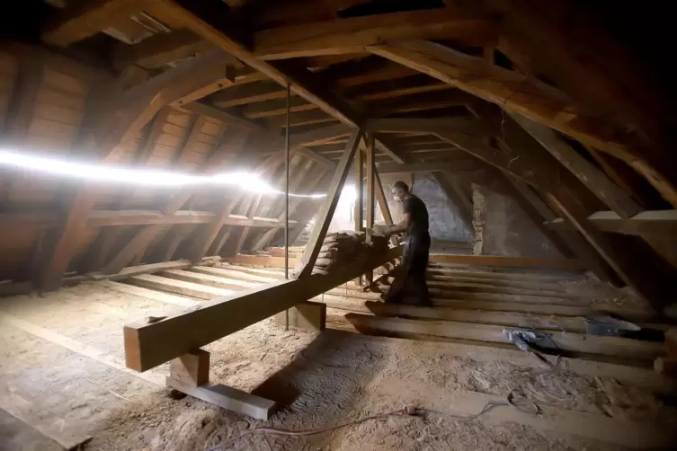 Im Speicher r&auml;umt ein Arbeiter die Gefache der Decke aus &ndash; h&auml;ndisch. 