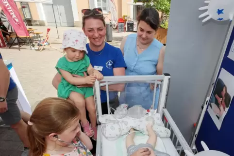Kinderkrankenschwester Elli Lajewski (Mitte) demonstriert Familie Maier die Versorgung eines Kindes.
