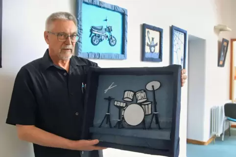 Der Künstler Michael Hamburger mit einer seiner Arbeiten – ein Bild mit einem Schlagzeug aus Jeansstoff. 