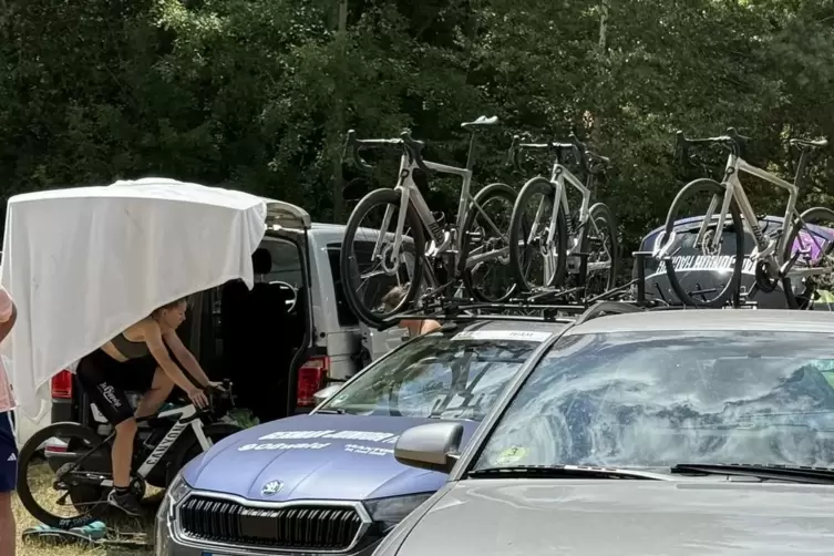 Teamfahrzeuge parken auf dem Parkplatz an der Hauptstra&szlig;e in Linden. Im Zelt f&auml;hrt sich eine Fahrerin auf der Rolle ein.
