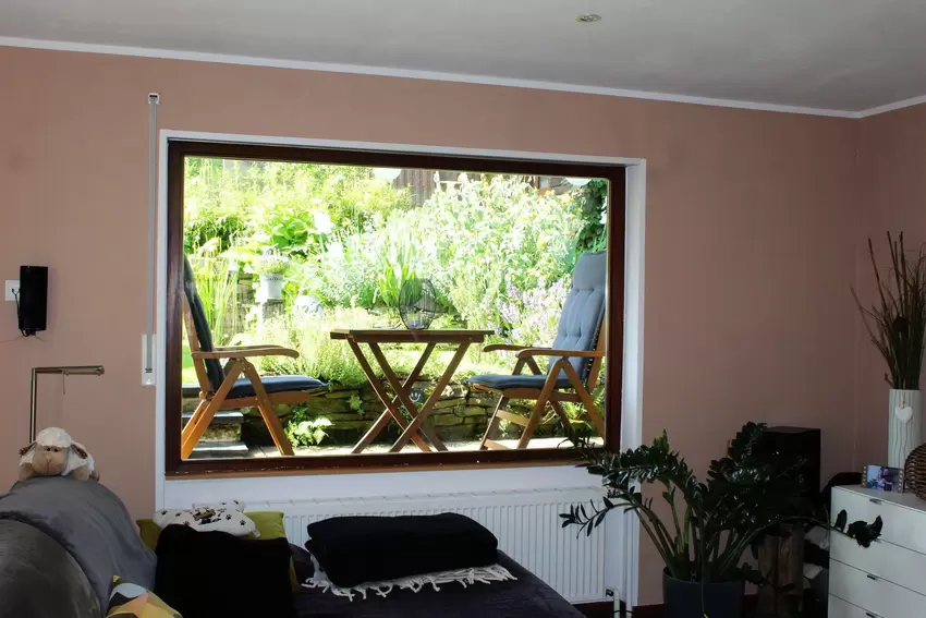 Durch die Fensterfront im gemütlichen Wohnzimmer lässt sich auch von drinnen ein Blick in den Garten werfen.