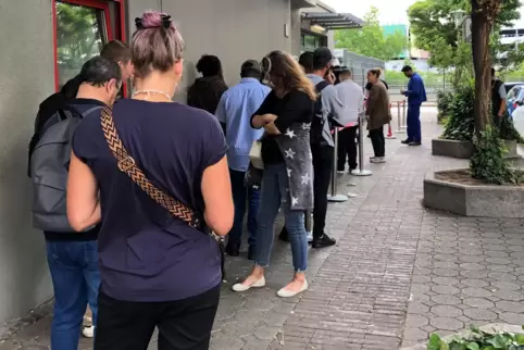 Warten auf dem Gehweg in der Mottstraße im Hemshof. Die Schlange derer, die ohne Termin in die Ausländerbehörde wollen, ist scho