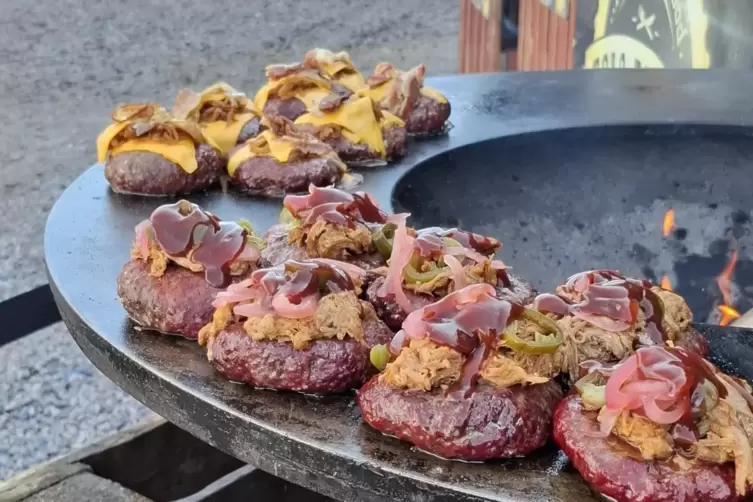 Burger Patties werden auf dem Feuerring zubereitet.