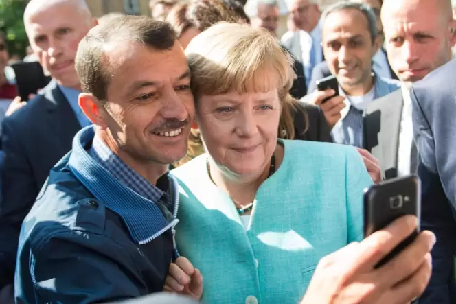 Selfie mit der Kanzlern: Angela Merkel lässt sich nach dem Besuch einer Erstaufnahmeeinrichtung für Asylbewerber mit einem Flüch